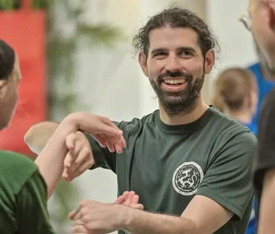 Lachend lid in groen WuDae-shirt tijdens een partneroefening